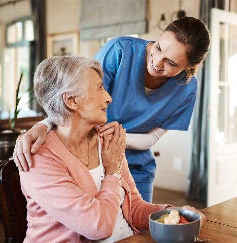 Care worker chatting with Elderly lady while she has breakfast